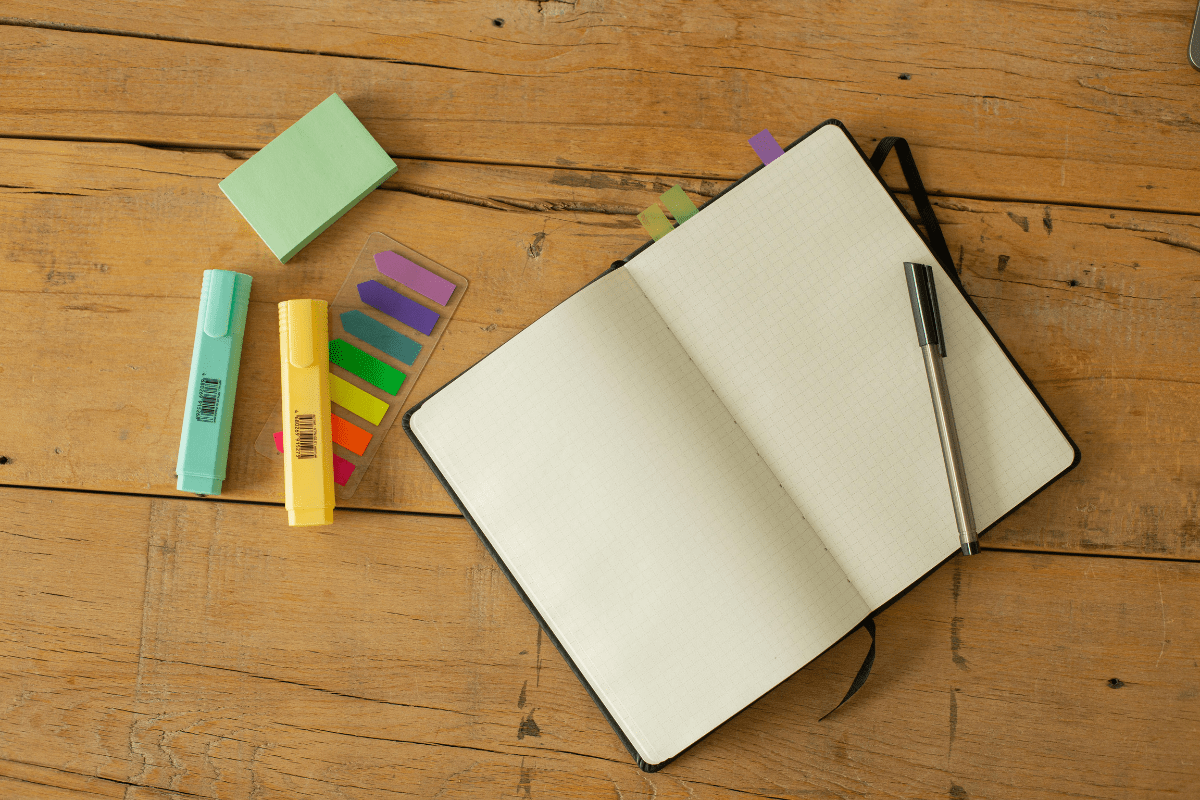 Image of an open notebook, pen and highlighters.